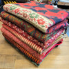 Stack of colorful 100% acrylic multi-pattern wool scarves in reds greens and golds ideal for summer evenings