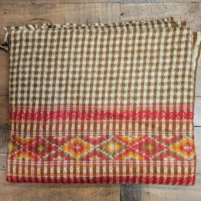 A folded 100% acrylic multi-pattern shawl blanket in earthy browns cream reds and orange for cozy summer evenings