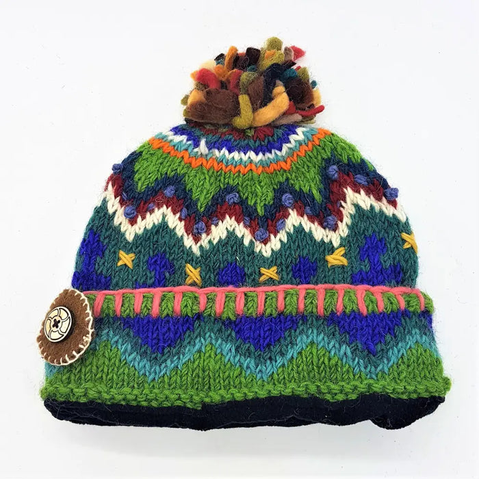 A wool bobble hat made from zealand wool with multicoloured felt bobble and green blue purple geometric pattern