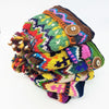 Stack of colourful hand knitted wool scarves with vibrant patterns and wool bobble hat with felt details from zealand wool