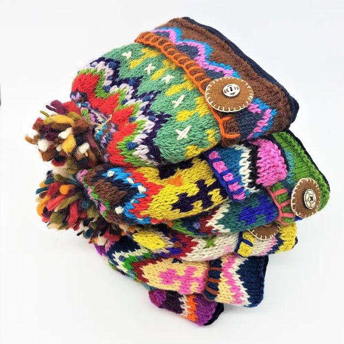 Stack of colourful hand knitted wool scarves with vibrant patterns and wool bobble hat with felt details from zealand wool