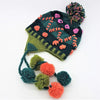 A dark green and teal wool bobble hat with pom-pom tassels and textured floral embroidery for kids and small adults