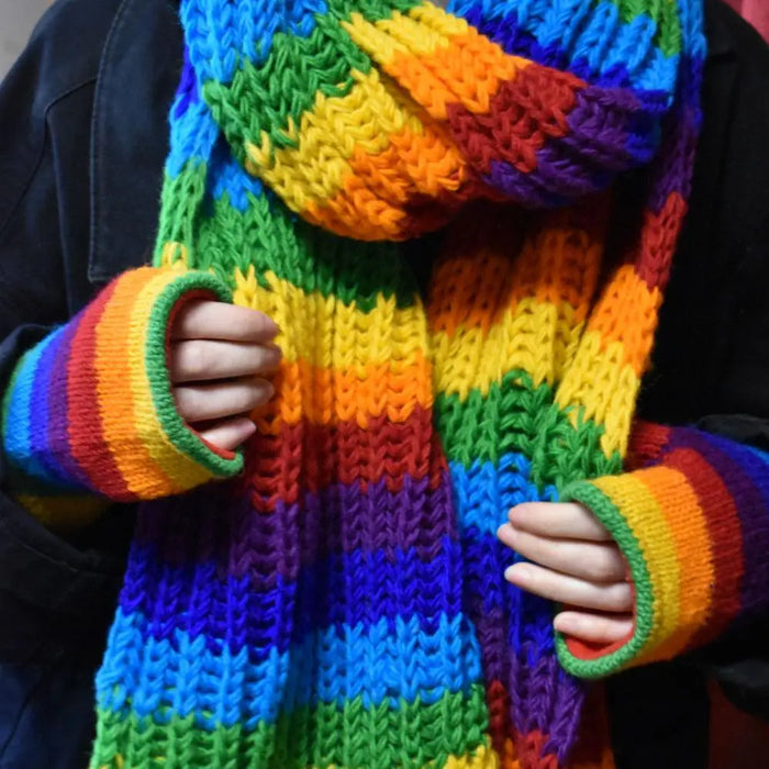 A vibrant wool rainbow handwarmer scarf with thick horizontal stripes in red orange yellow green blue and purple