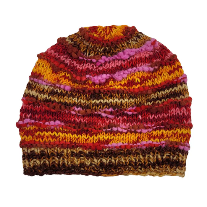 A hand-knitted wool slouch beanie hat with red orange pink and brown stripes and a ribbed texture made from zealand wool