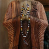 A colorful beaded mala necklace with multicolored gemstones and tassel draped on a wooden statue planet astro style