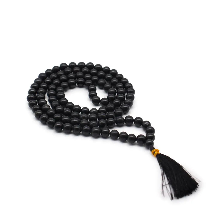 Black agate mala necklace with 108 black beads, gold-colored knot, black tassel, and velvet pouch background