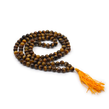 A coiled 108 bead mala necklace made of polished tiger eye with a vibrant orange tassel and velvet pouch nearby