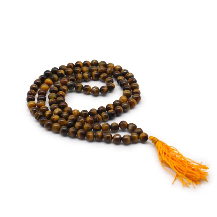 A coiled 108 bead mala necklace made of polished tiger eye with a vibrant orange tassel and velvet pouch nearby