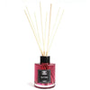 A glass bottle reed diffuser with pink fig and cassis liquid and light reed sticks in a black cap and label