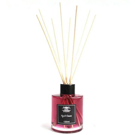 A glass bottle reed diffuser with pink fig and cassis liquid and light reed sticks in a black cap and label
