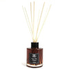 A sleek amber glass bottle reed diffuser with a black cap and light beige wooden reeds for ginger stem scent