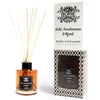 A glass reed diffuser with amber fragrance oil and beige wooden reeds in a black capped glass bottle