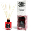 Red glass bottle reed diffuser with black cap and wooden sticks labeled pomegranate and nutmeg by at home