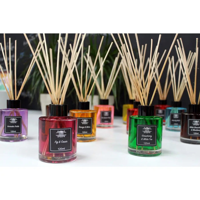 A collection of colorful glass bottle reed diffusers with black caps labeled vanilla plantation scents