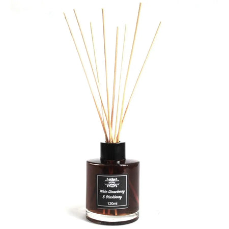 A dark amber glass bottle reed diffuser with black cap and light wooden reeds for white strawberry scent
