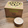 A beige organic scented tealight candle in a metallic tin next to its cardboard box labeled patchouli vanilla six fragrances india organic