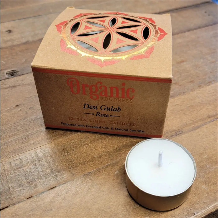 A white organic scented tealight candle in a metal tin beside its brown box with india organic red and gold design