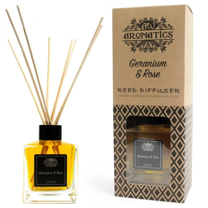 A clear glass reed diffuser bottle with golden-yellow geranium and rose essential oil and black cap with rattan sticks