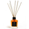 Clear glass reed diffuser with black cap filled with amber mandarin essential oil and wooden reeds of ylang ylang scent