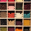 A collection of colorful 21cm non-drip bistro wax dinner candles neatly arranged in a wooden grid sold individually