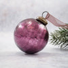 A 3 inch mulberry crackle glass christmas bauble with a brass cap and a sheer mauve ribbon hanging