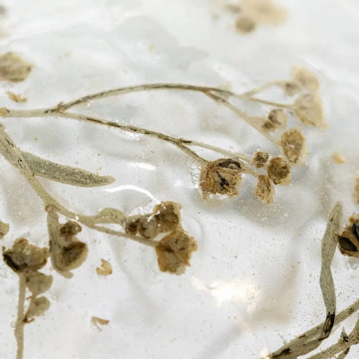 A 3 inch spray botanical bauble with slender brown dried flowers encased in clear resin