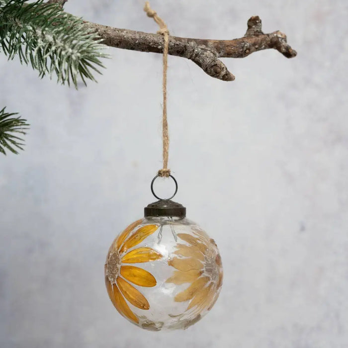 A 3 inch zinnea botanical clear glass bauble with a hand painted yellow daisy floral design and rustic twine hanging