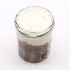 A clear glass jar with a fragranced sugar body scrub layered with brown espresso sugar and white creamy top