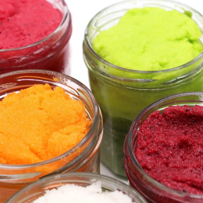 Vibrant peach sangria sugar body scrub with shea butter in clear glass jars showing textured bath salts