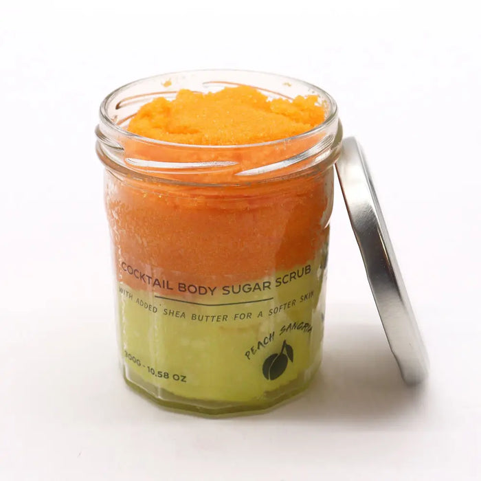 A vibrant orange peach sangria sugar body scrub with shea butter in a clear glass jar with a silver lid