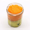 A vibrant orange peach sangria sugar body scrub with shea butter in a clear glass jar and pale green label