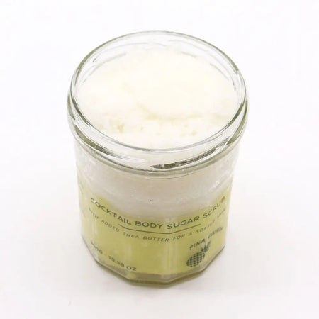 Pineapple-scented pina colada sugar body scrub with shea butter in clear glass jar with pale yellow label 300g