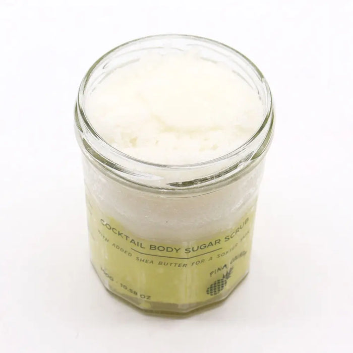 Pineapple-scented pina colada sugar body scrub with shea butter in clear glass jar with pale yellow label 300g