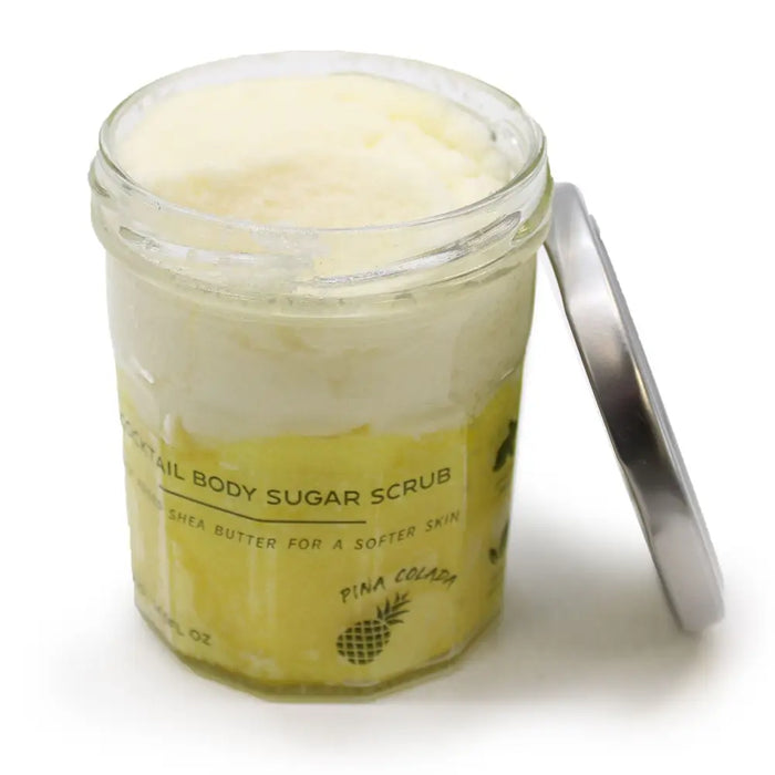 A clear glass jar with a silver lid containing 300g pina colada sugar body scrub with shea butter