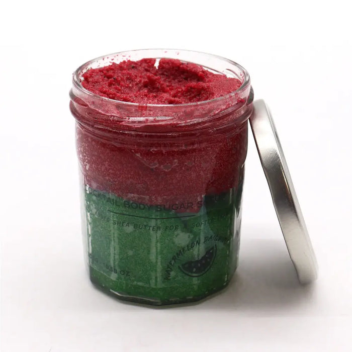A clear glass jar with silver lid holds a vibrant red watermelon daquiri body sugar scrub for dry skin care