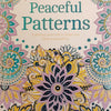 Adult colouring book peaceful patterns by Charlie Wood-Penn with intricate mandala floral designs in teal gold and lavender on cream