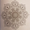 A detailed black line drawing of a symmetrical mandala with hearts and floral patterns in an adult colouring book