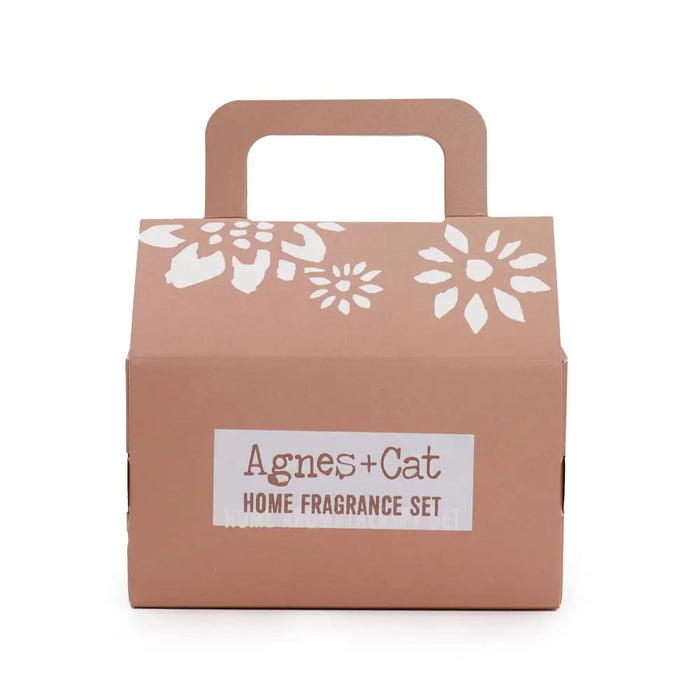 A taupe cardboard gift set with white floral cutouts and handle labeled agnes cat home fragrance set for cat fragrance gift