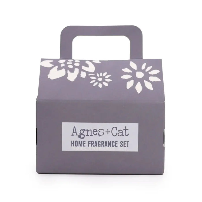 A purple cardboard fragrance gift set box with white floral pattern and handle labeled agnes cat home fragrance set