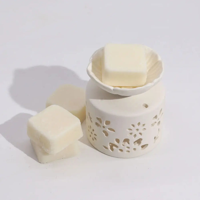 Cream-colored ceramic wax melt burner with floral cutouts and matching wax cube in agnes & cat fragrance gift set windermere