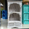 A rustic whitewashed wooden albasia bathroom cabinet with carved floral and scrollwork details on shelves and drawers
