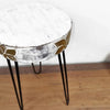 A round distressed white and gold albasia wood plant stand with slender black hairpin legs