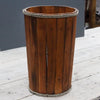 A rustic albesia wood storage tub with vertical slats, brown finish, and thick gray rope accents on top and bottom edges