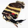Hand-knitted wool beanie with earthy brown and cream stripes featuring colorful tassels and decorative pom-poms