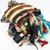 A colorful wool and silk beanie with brown, cream, black stripes, tassels, flowers, and pom-poms for adults