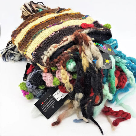 A colorful wool and silk beanie with brown, cream, black stripes, tassels, flowers, and pom-poms for adults
