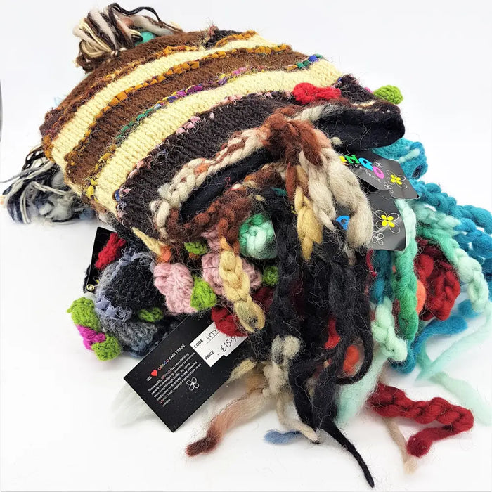A colorful wool and silk beanie with brown, cream, black stripes, tassels, flowers, and pom-poms for adults