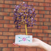 Amethyst gemstone tree with purple amethyst crystals and golden wire branches on a white stone base with a painted flower