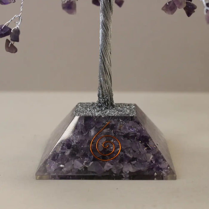 A purple amethyst gemstone tree with twisted silver wire trunk and heart charms on a resin base with crushed stones