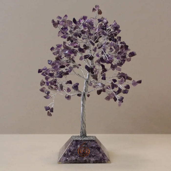 A purple amethyst gemstone tree with silver wire frame and organite pyramid base filled with embedded crystals